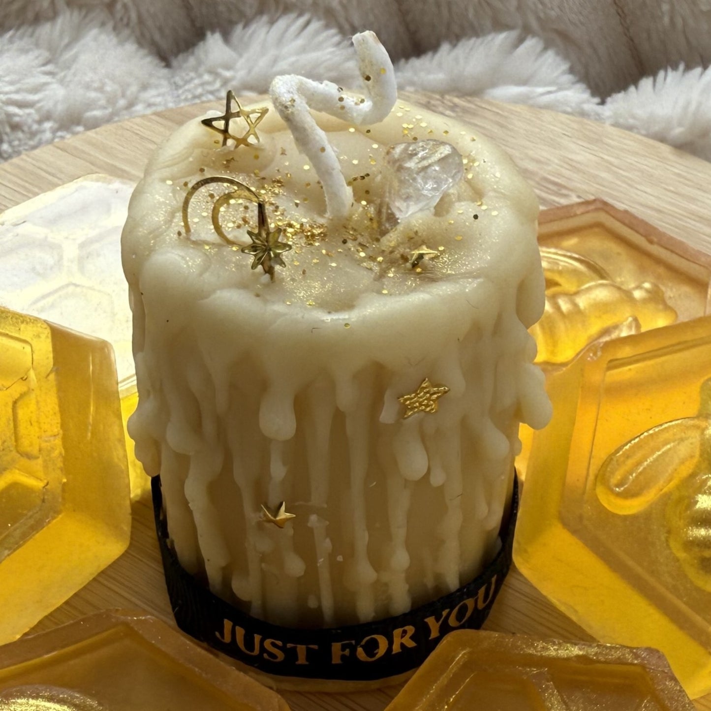 Beeswax candle with gold stars and 'JUST FOR YOU' ribbon on a textured surface.