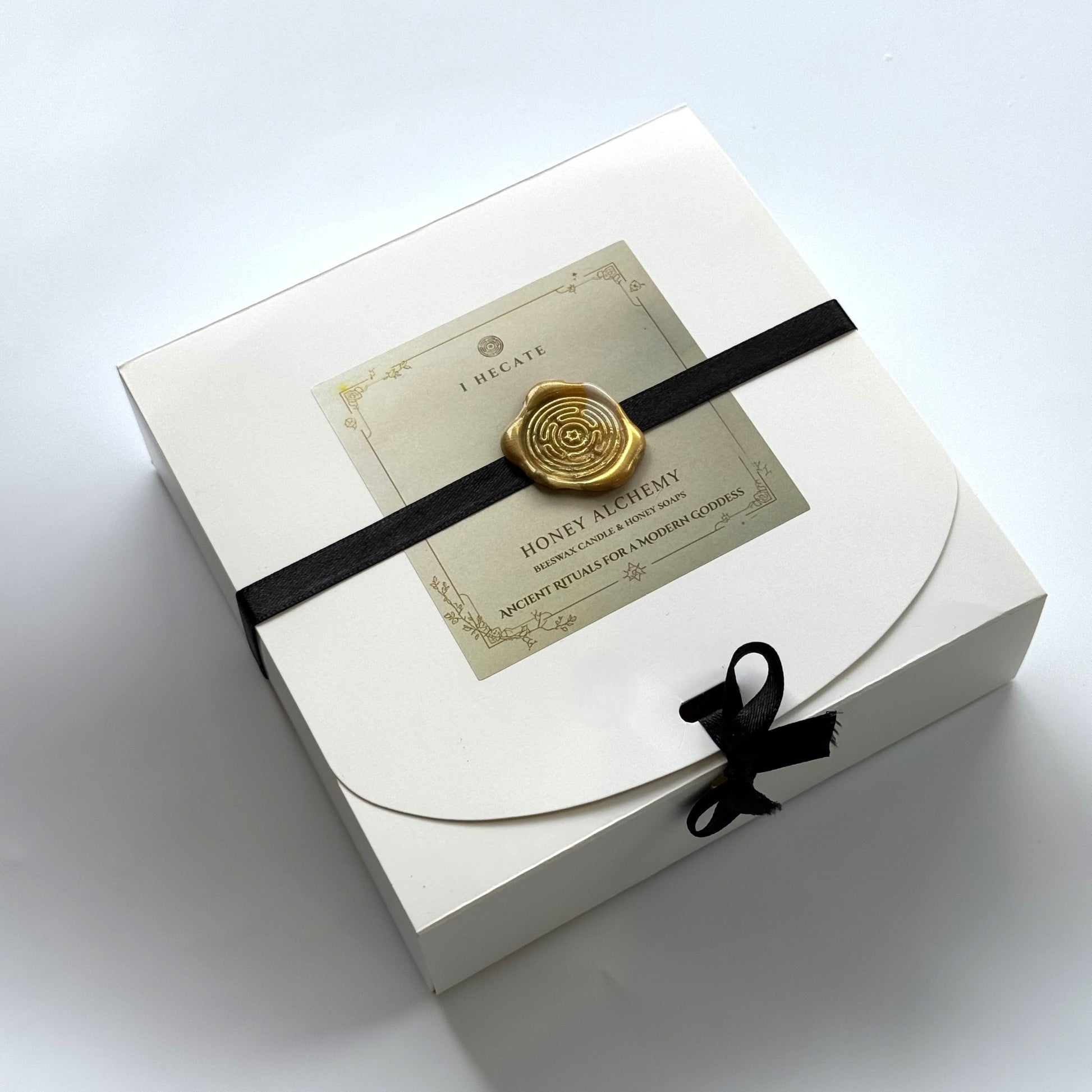 White gift box with a black ribbon and decorative label on a white background