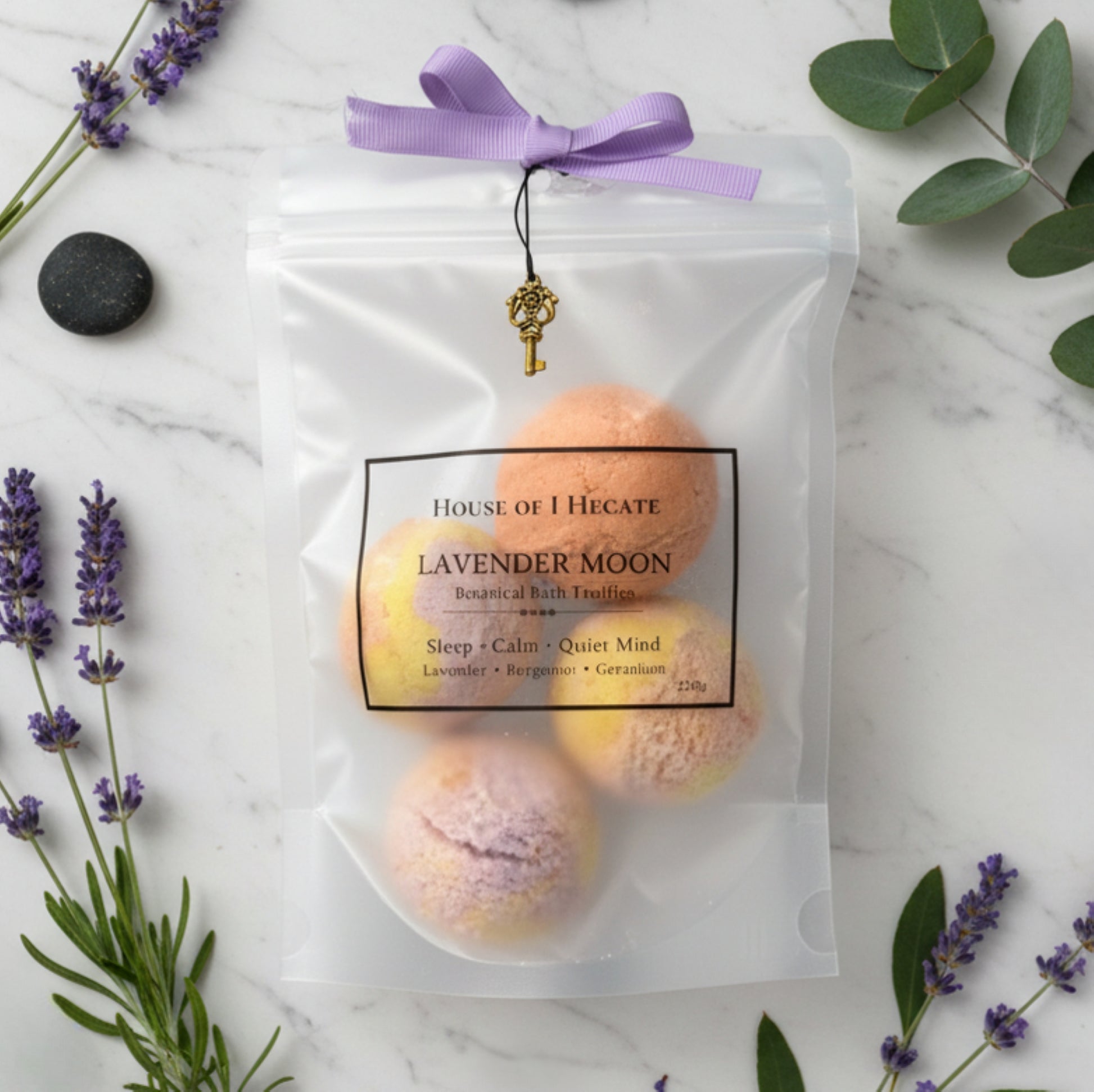 Packaged lavender bath truffles with a purple ribbon on a marble surface with lavender flowers.