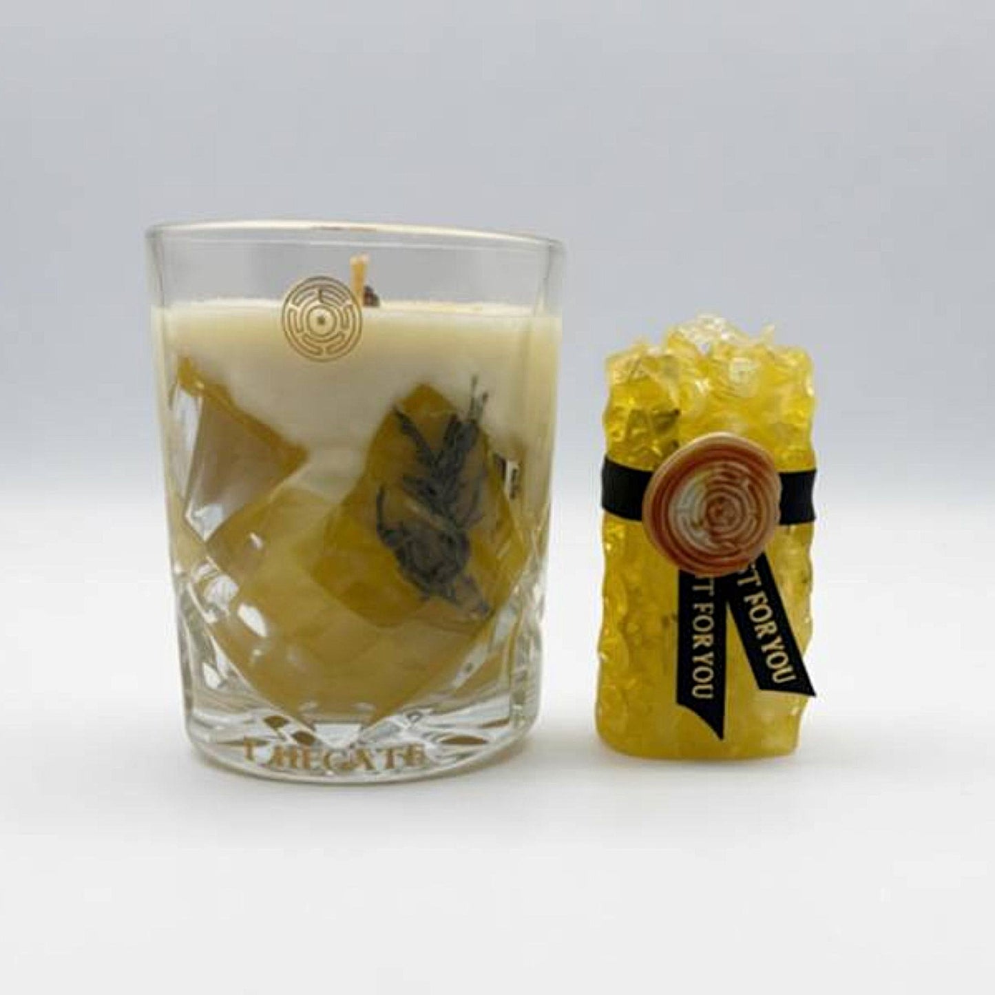 Beeswax candle with decorative elements and a wrapped soap on a white background